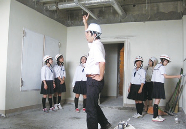 生徒がヘルメットをかぶり、工事現場の見学